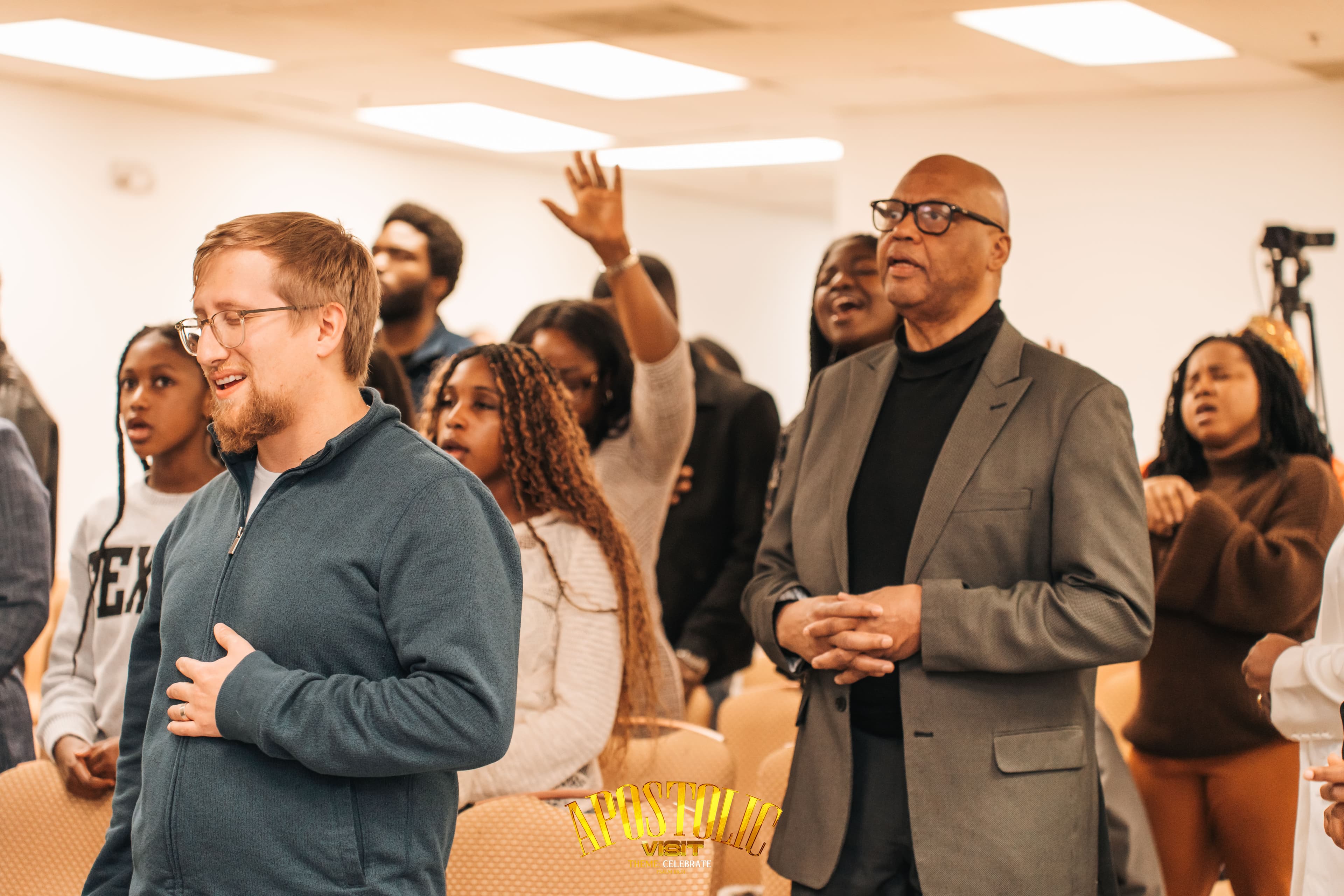 Diverse congregation members praying and singing during an apostolic visit church service.